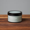 Load image into Gallery viewer, Drift & Sage scented soy candle in black metal tin on wooden surface.