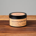 Load image into Gallery viewer, Island Pumpkin Walk scented soy candle in a 6oz matte metal tin placed on a wooden cutting board with a light gray background.