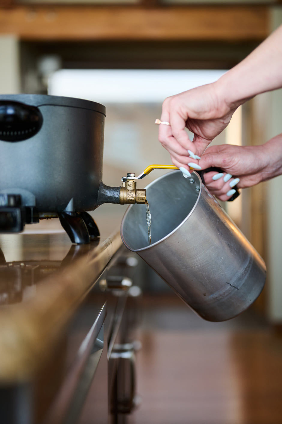 a hand pouring wax into a bucket to make candles