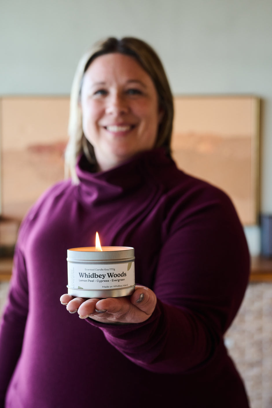 a woman holding a lit candle out and smiling