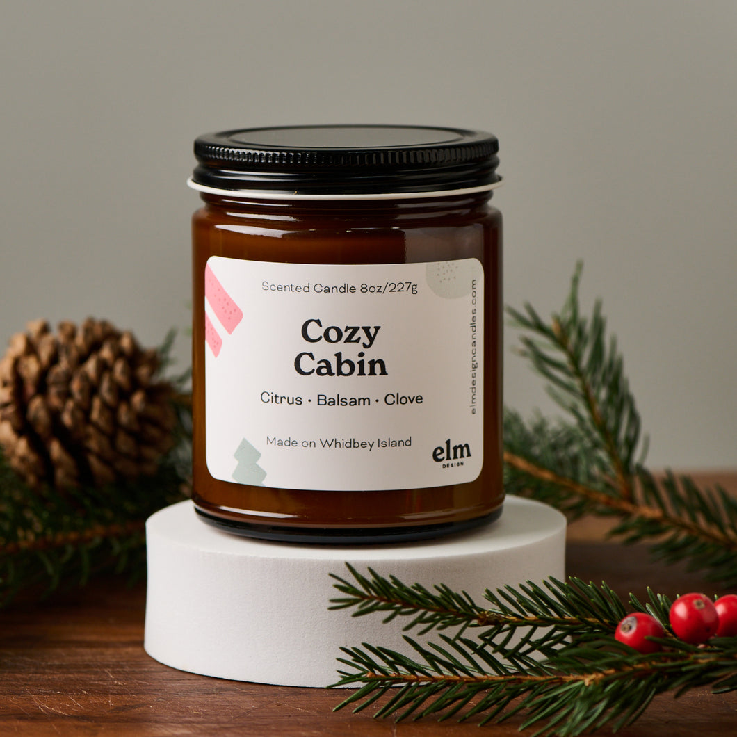 Elm Design's Cozy Cabin scented candle in an 8oz glass jar.