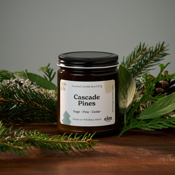 a candle sitting in front of pine needles