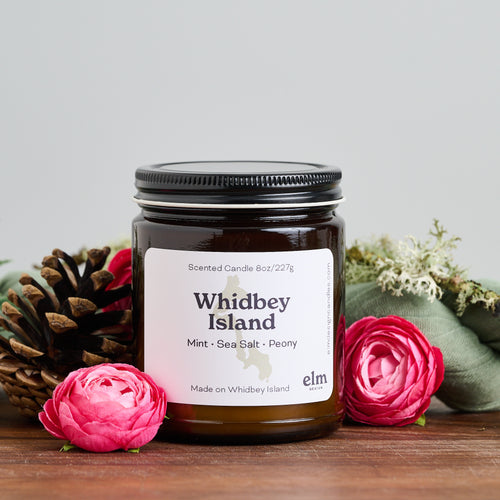 Elm Design Candles scented candle in Whidbey Island scent in 8oz amber glass jar.