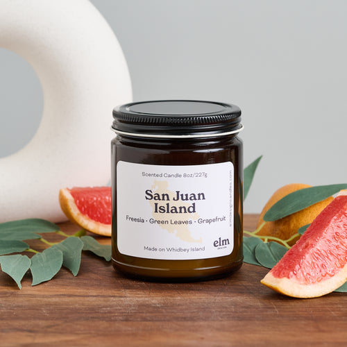 Elm Design Candles scented candle in San Juan Island scent in 8oz amber glass jar.