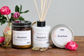 Load image into Gallery viewer, Elm Design Candles' scent Rosebud in a group shot of an 8oz amber glass jar, a 4oz reed diffuser and a 6oz metal tin.
