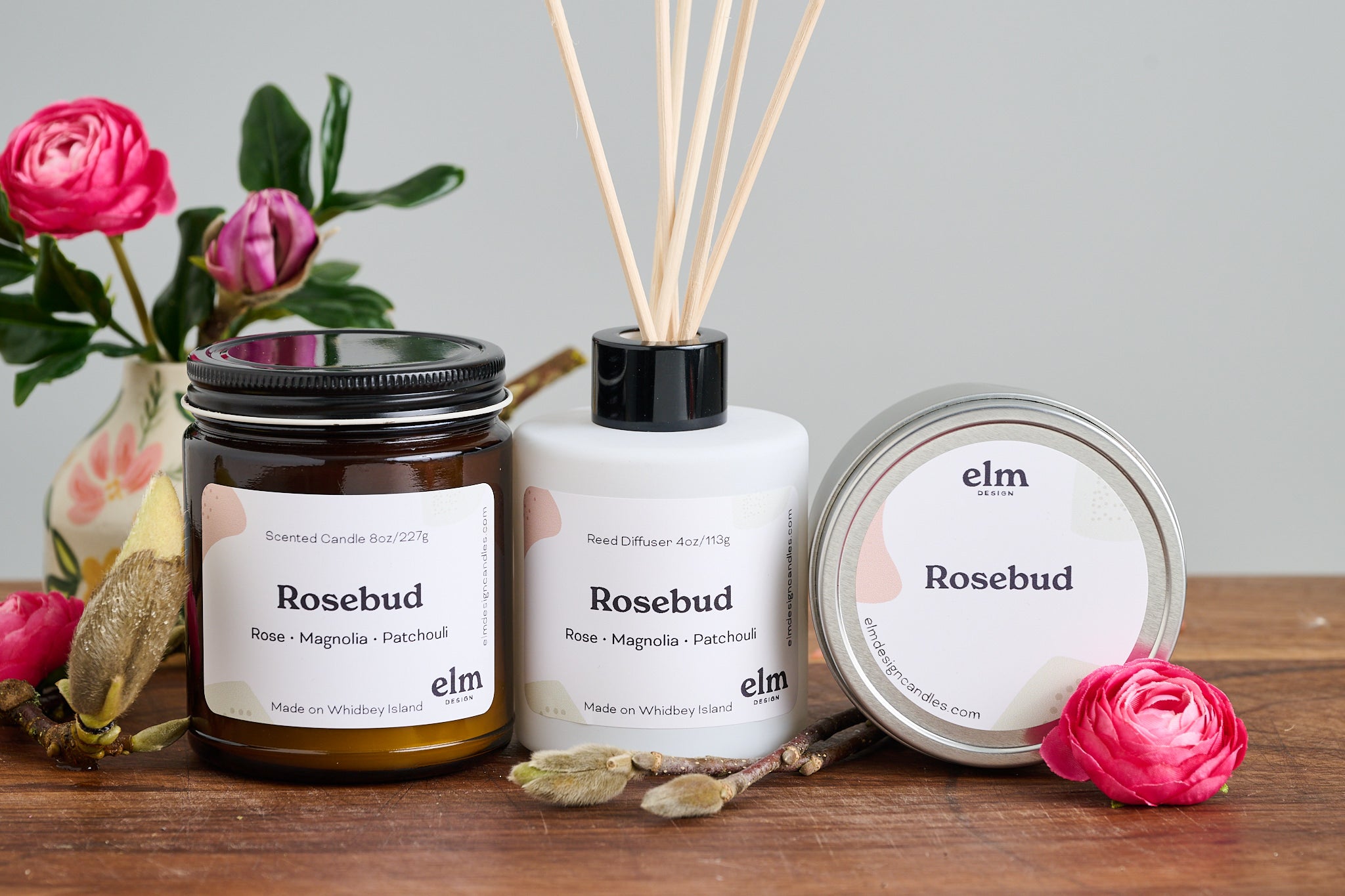 Elm Design Candles' scent Rosebud in a group shot of an 8oz amber glass jar, a 4oz reed diffuser and a 6oz metal tin.