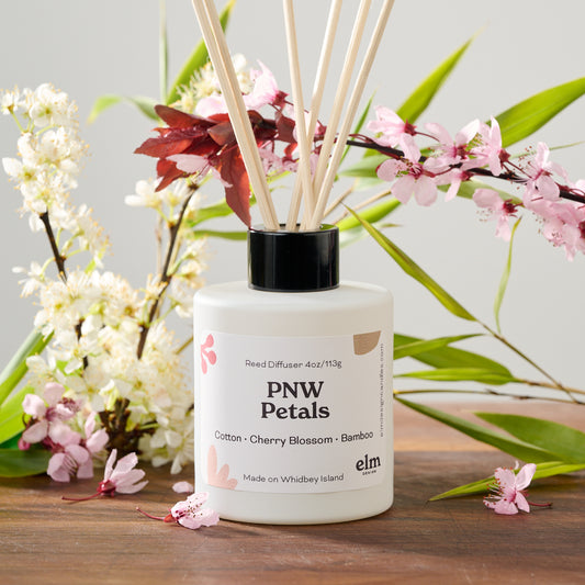 PNW Petals reed diffuser in a 4oz white glass jar with reeds.