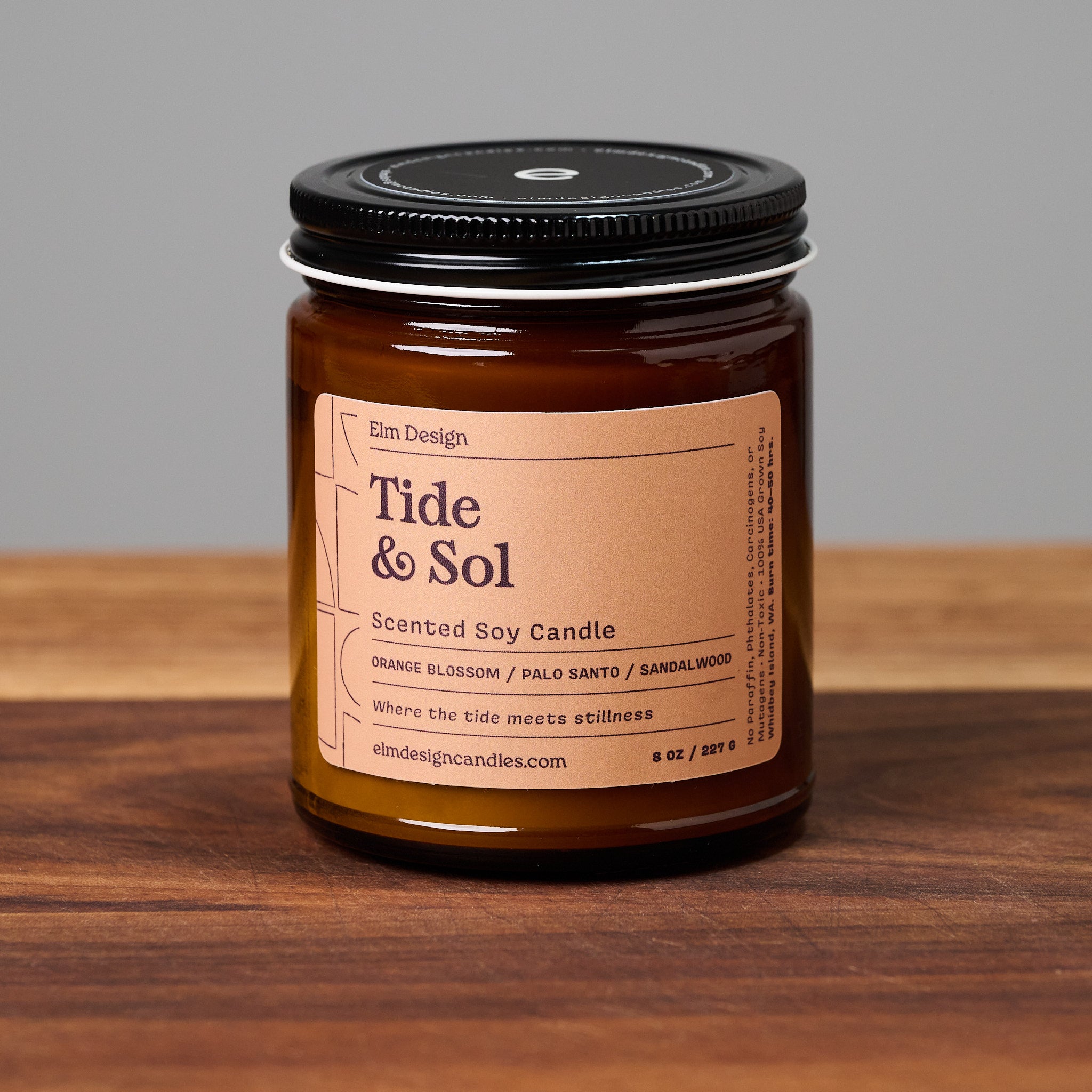 Tide & Sol scented soy candle in amber glass jar on wooden surface.