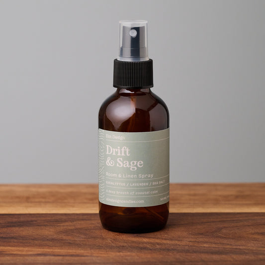Drift & Sage scented room spray in amber glass jar on wooden surface.