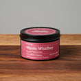Load image into Gallery viewer, A black metal tin candle with a dark pink label reading 'Mystic Whidbey' sits on a wooden surface against a light gray background.
