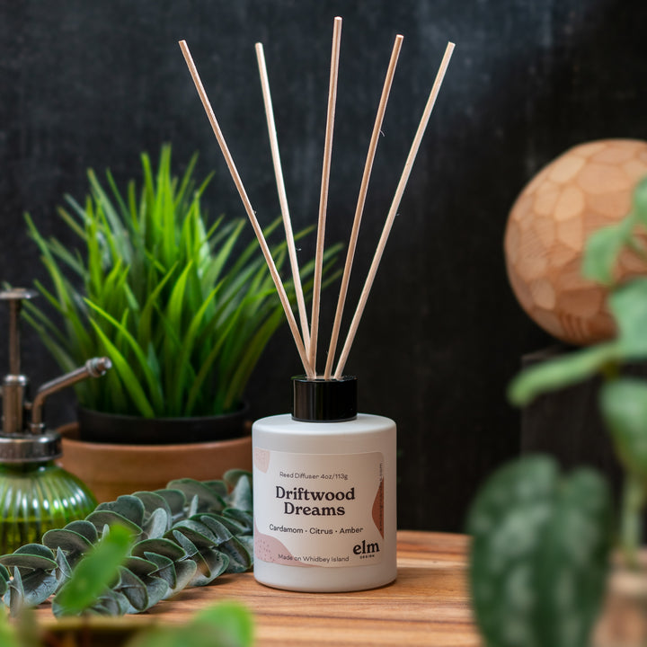 a reed diffuser set up in front of green leaves