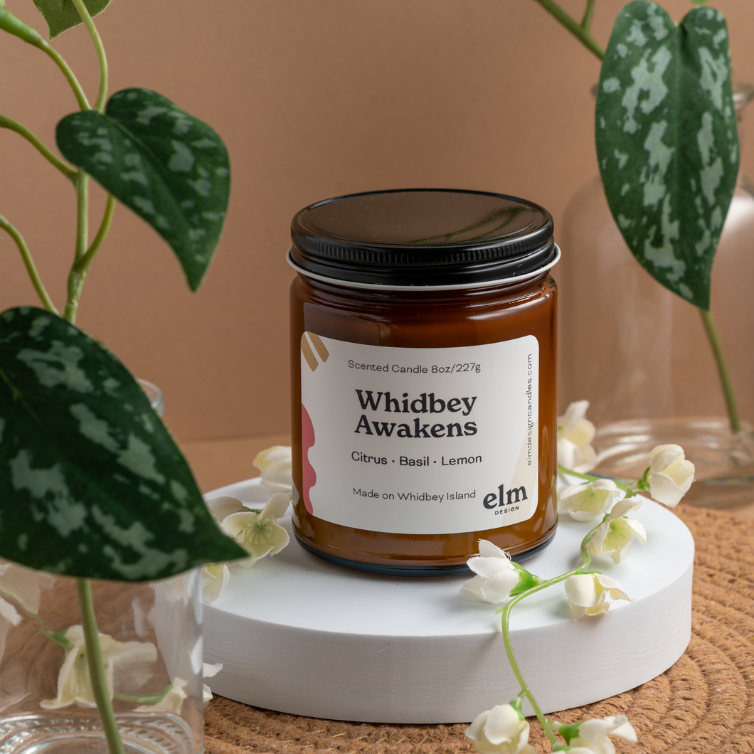 Whidbey Awakens scented soy candle in colorfully labeled 8 oz container.